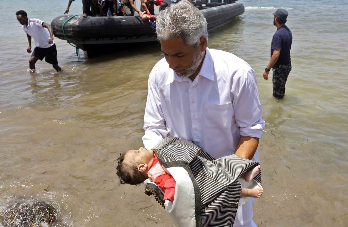 A man carries the body of one of the three babies.