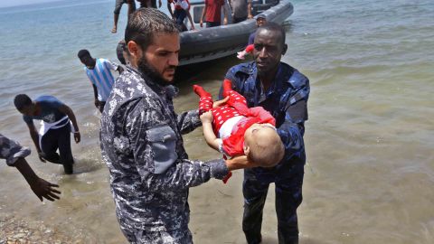 Survivors arrive on shore as two men hold the body of one of the three babies.