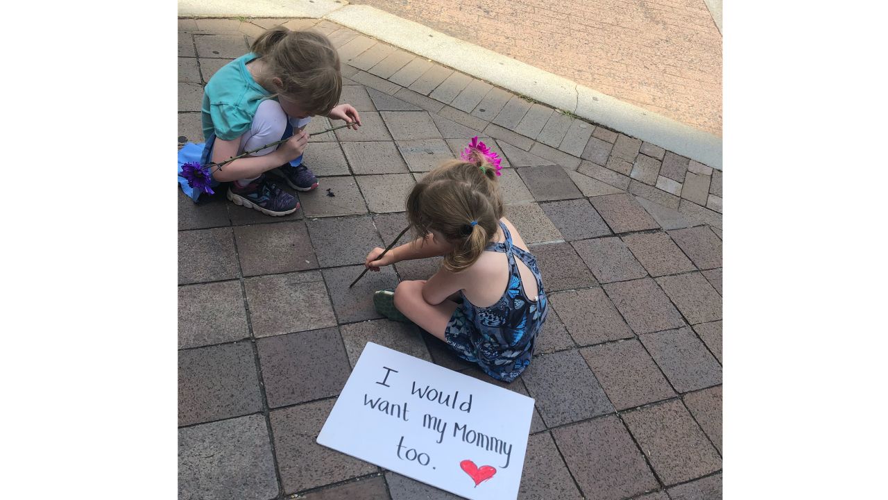 Genevieve Cammack, 5, and Neve Cammack, 4, attended the "Families Belong Together" rally with their mother. Here they sit outside the Trump International Hotel in Washington.