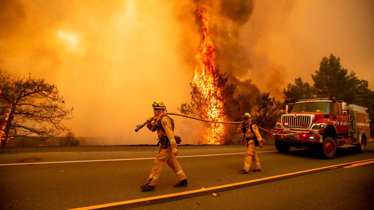 Firefighters try to stop a wildfire as wind drives embers across Highway 20 near Clearlake Oaks, Calif., on Sunday, July 1, 2018. (AP Photo/Noah Berger)