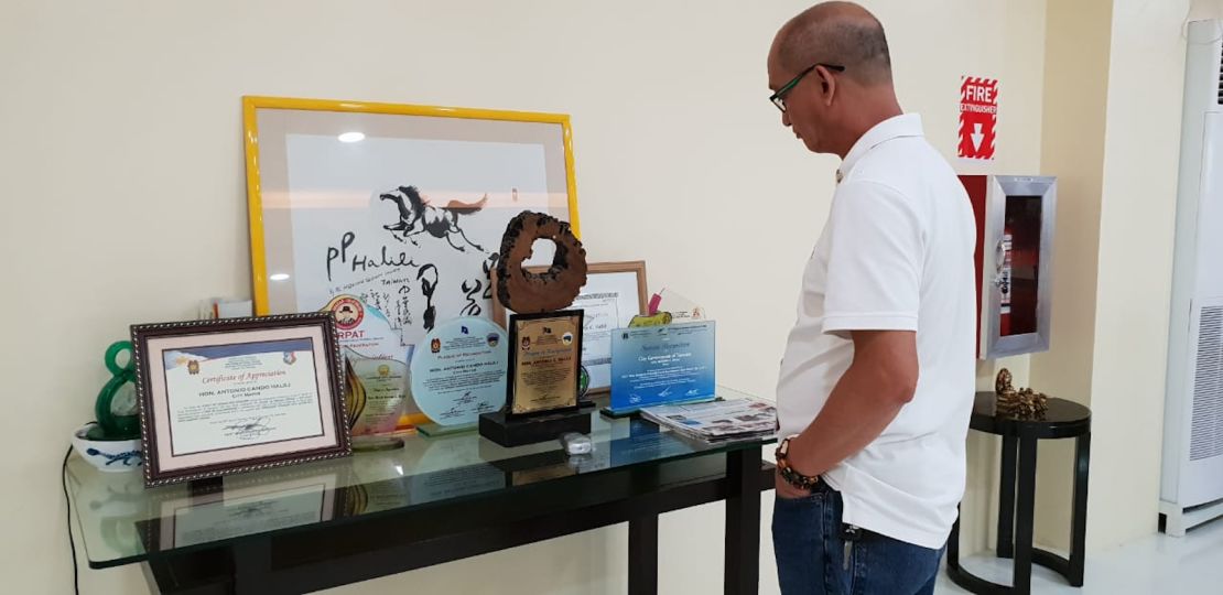 Mayor Halili's aide Carlos Mojares looks at his boss' awards and trophies. He says Halili was incredibly proud of his collection.