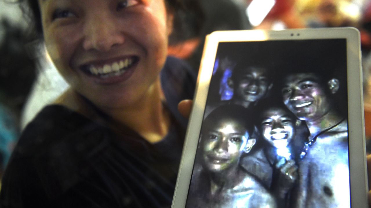A family member shows a picture of four of the twelve missing boys near the Tham Luang cave at the Khun Nam Nang Non Forest Park in Mae Sai on July 2, 2018.