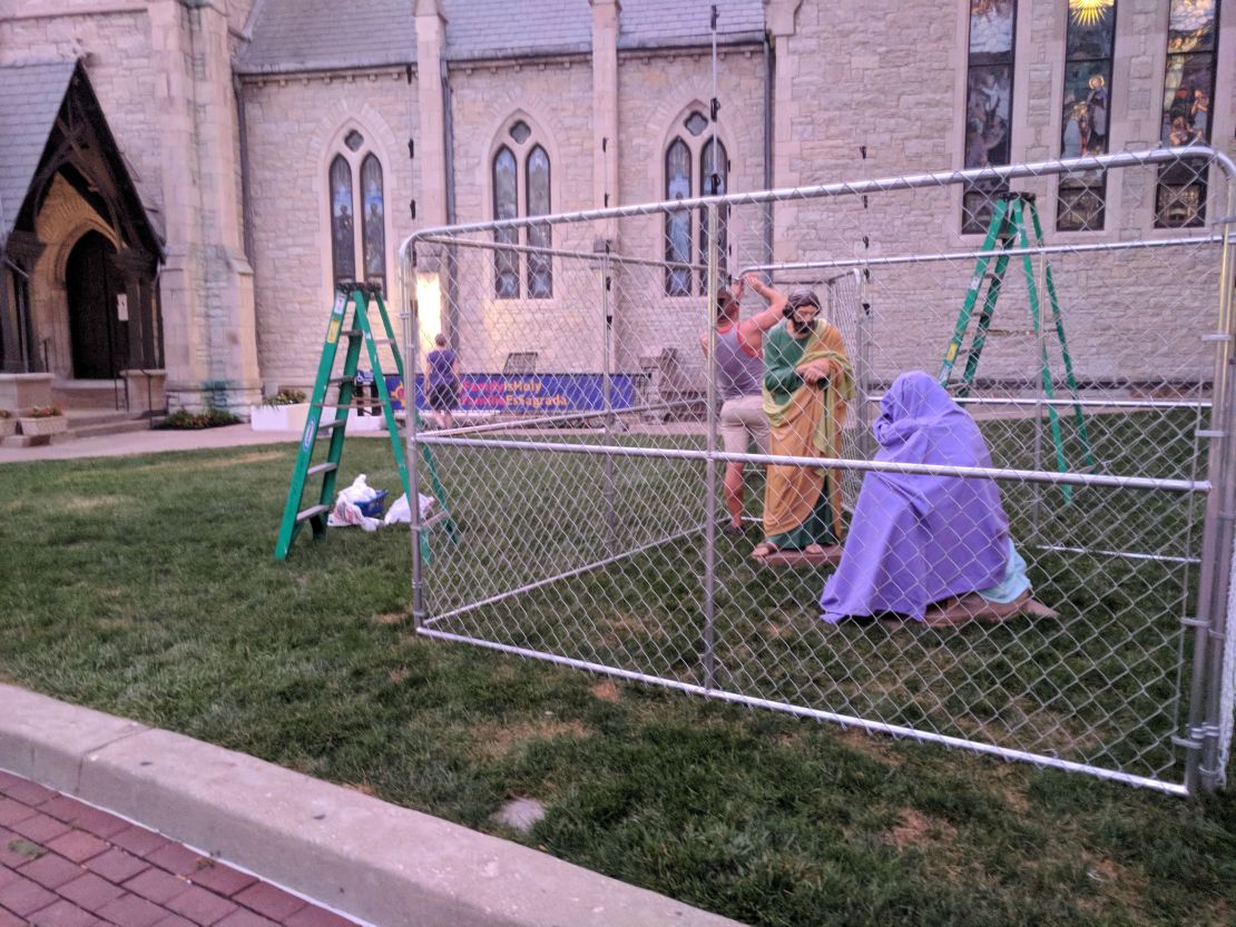 A Christ Church Cathedral volunteer sets up a display of the Holy Family in a cage to protest US immigration policy.