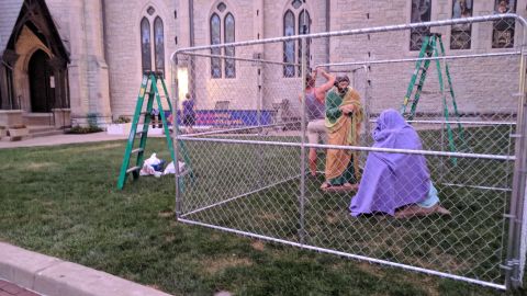 A Christ Church Cathedral volunteer sets up a display of the Holy Family in a cage to protest US immigration policy.