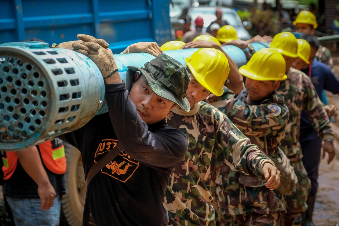 Rescue workers carry heavy water pumping equipment into Tham Luang Nang Non cave on July 1.