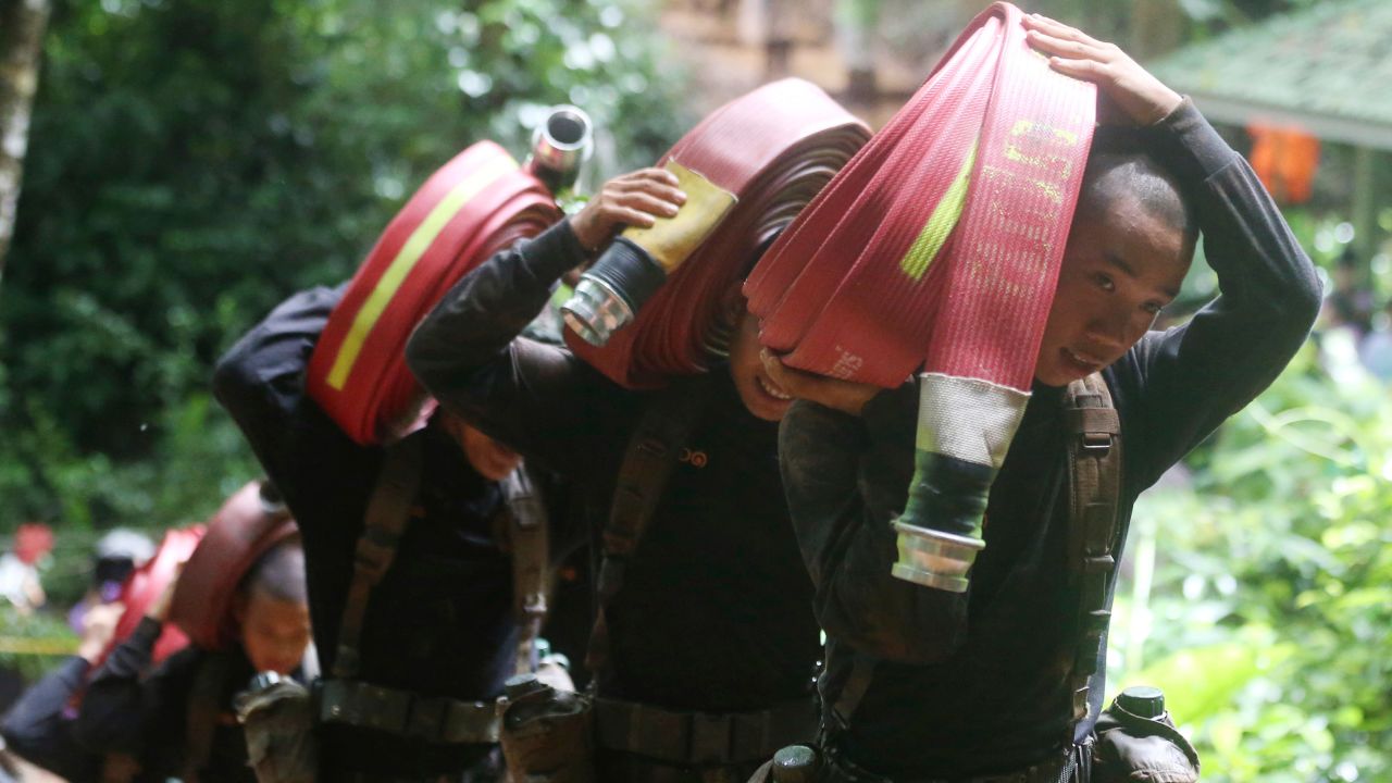 Thai soldiers carry hoses and additional water pumps during the search for the soccer team.