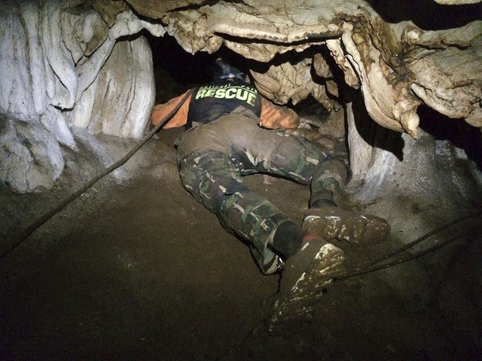 A rescuer looks for a cave entrance on June 27.