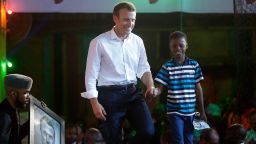 French President Emmanuel Macron, left, walk on the stage with 11 years -old, Kareem Waris Olamilekan,a young Nigerian artist who drew the portrait of President Macron. 