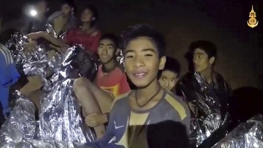 In this July 3, 2018, image taken from video provided by the Royal Thai Navy Facebook Page, Thai boys smile as Thai Navy SEAL medic help injured children inside a cave in Mae Sai, northern Thailand.  The Thai soccer teammates stranded more than a week in the partly flooded cave said they were healthy on a video released Wednesday, as heavy rains forecast for later this week could complicate plans to safely extract them. (Royal Thai Navy Facebook Page via AP)