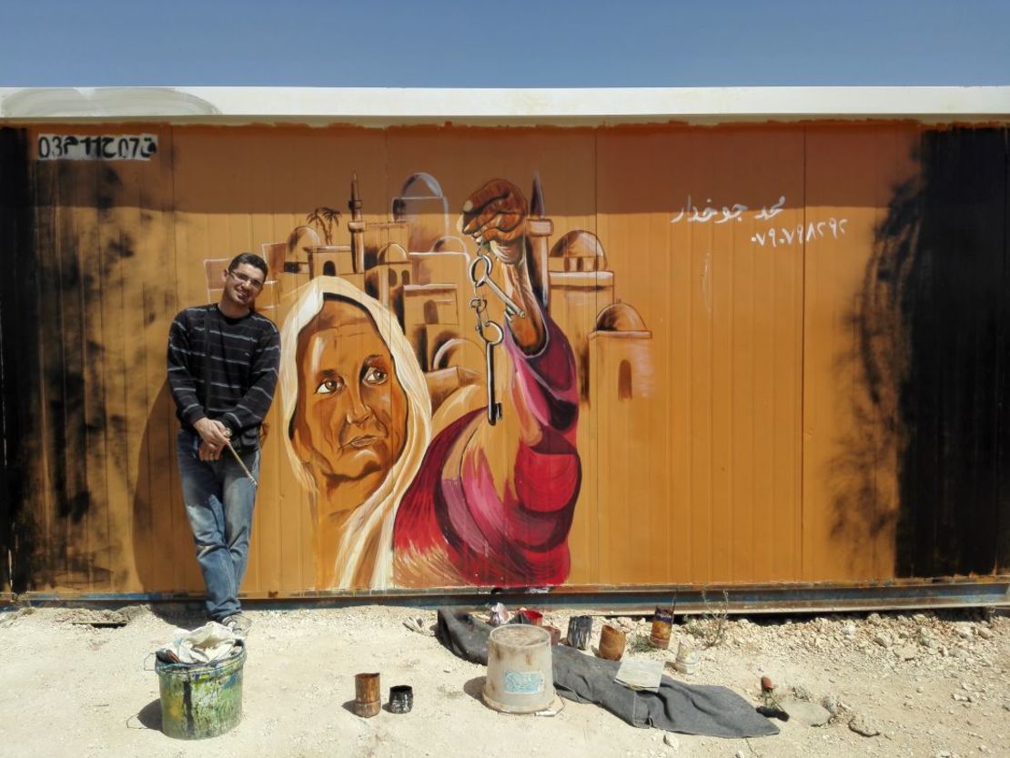 Syrian refugee Mohamed Jokhadar in front of a mural he painted at the Zaatari Camp in Jordan.