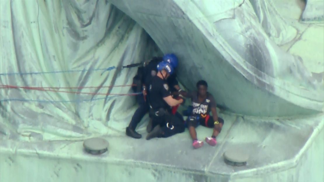 Police prepare to bring a protester down from the base of the Statue of Liberty on July 4, 2018.