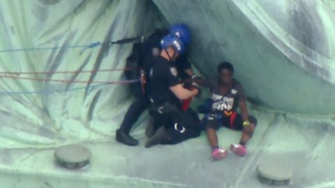 Police prepare to bring a protester down from the base of the Statue of Liberty on July 4, 2018.