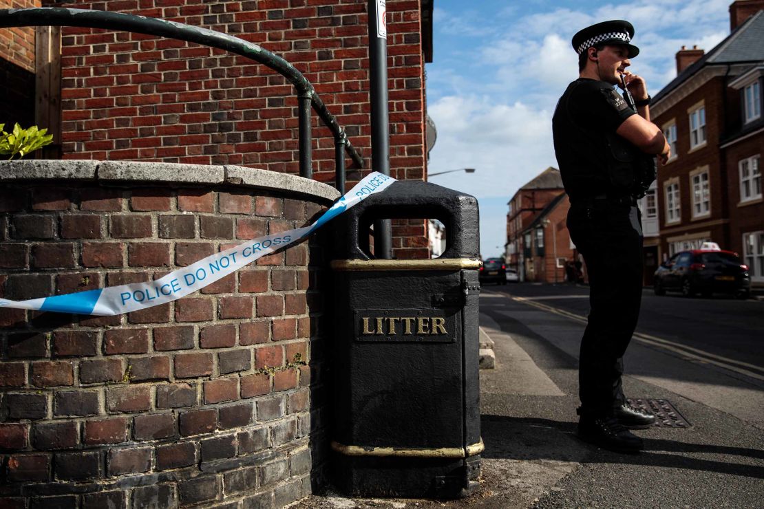 A police officer stands at a cordon around a public trash can Wednesday next to a supported housing project in Salisbury, thought to be connected to the Amesbury victims.