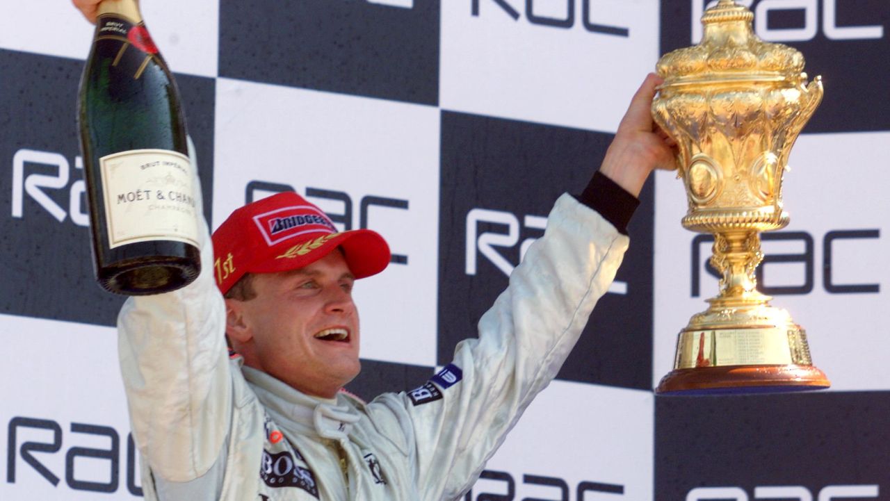 SILVERSTONE, UNITED KINGDOM:  Scottish McLaren-Mercedes driver David Coulthard holds his trophy on the podium after winning the 50th British Formula One Grand Prix on the Silverstone racetrack,11 July 1999. Scottish McLaren-Mercedes driver David Coulthard won the race ahead of Irish Ferrari driver Eddie Irvine finished and German Willimas-Supertec driver Ralf Schumacher.  (ELECTRONIC IMAGE) (Photo credit should read PATRICK HERTZOG/AFP/Getty Images)
