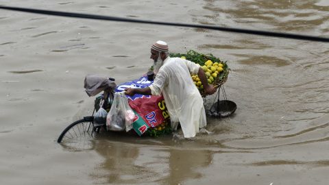 A street vendor in Lahore pushes a bike loaded with mangoes through the flooded streets on July 3, 2018.