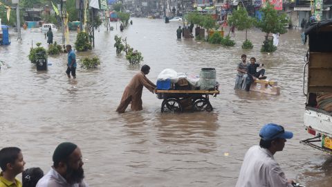 Pakistani residents cross a flooded street in Lahore after monsoon rains on July 3, 2018.