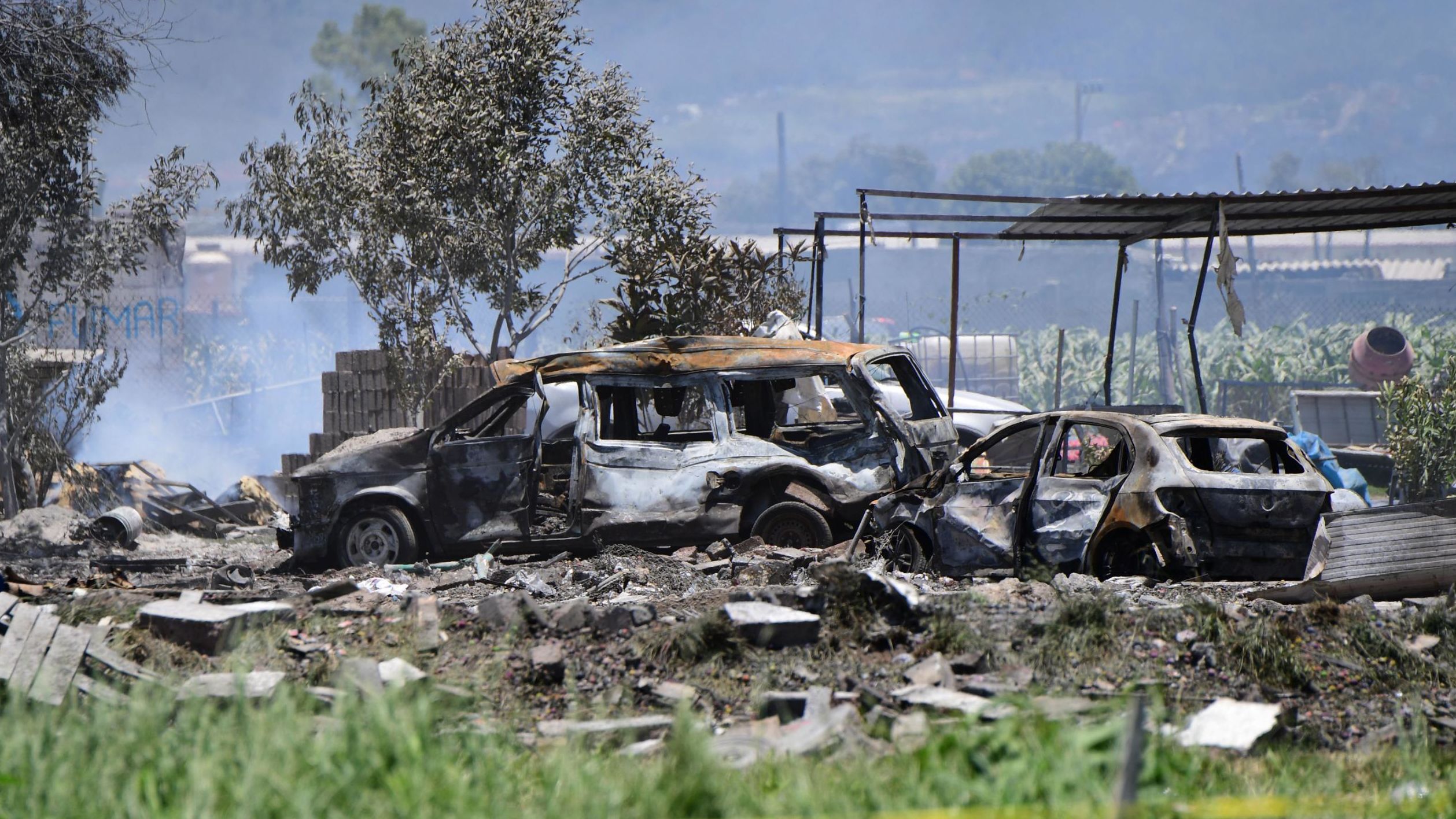 Charred vehicles remain at the site of explosions at warehouses in Tultepec. 