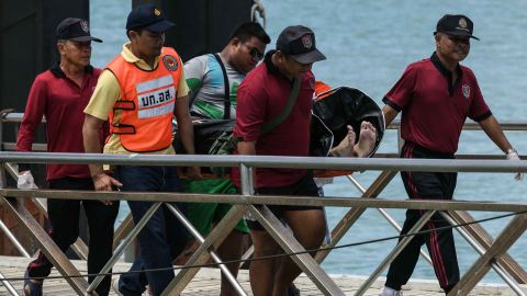 Thai rescue personnel carry one of the deceased passengers recovered from the capsized tourist boat.