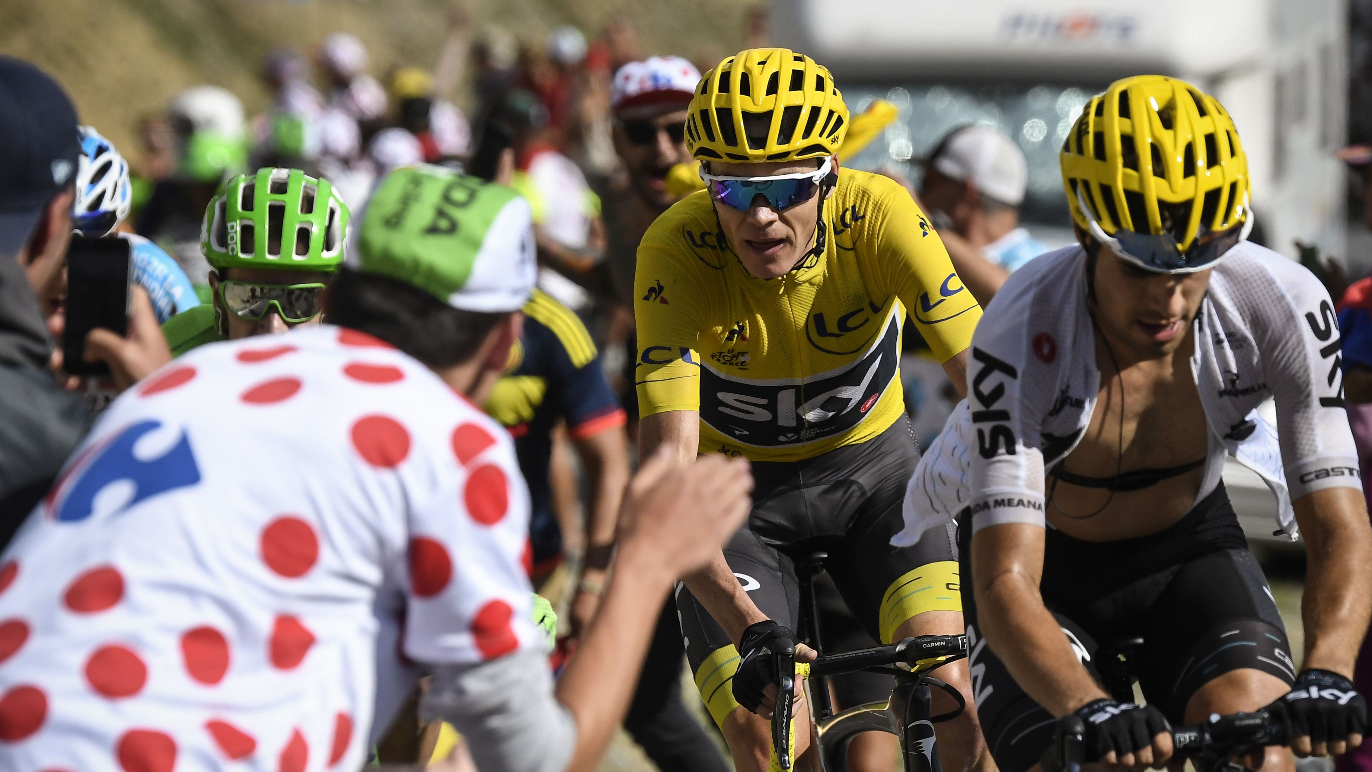 Chris Froome (in yellow) rides uphill through crowds of fans during the 2017 Tour de France. 
