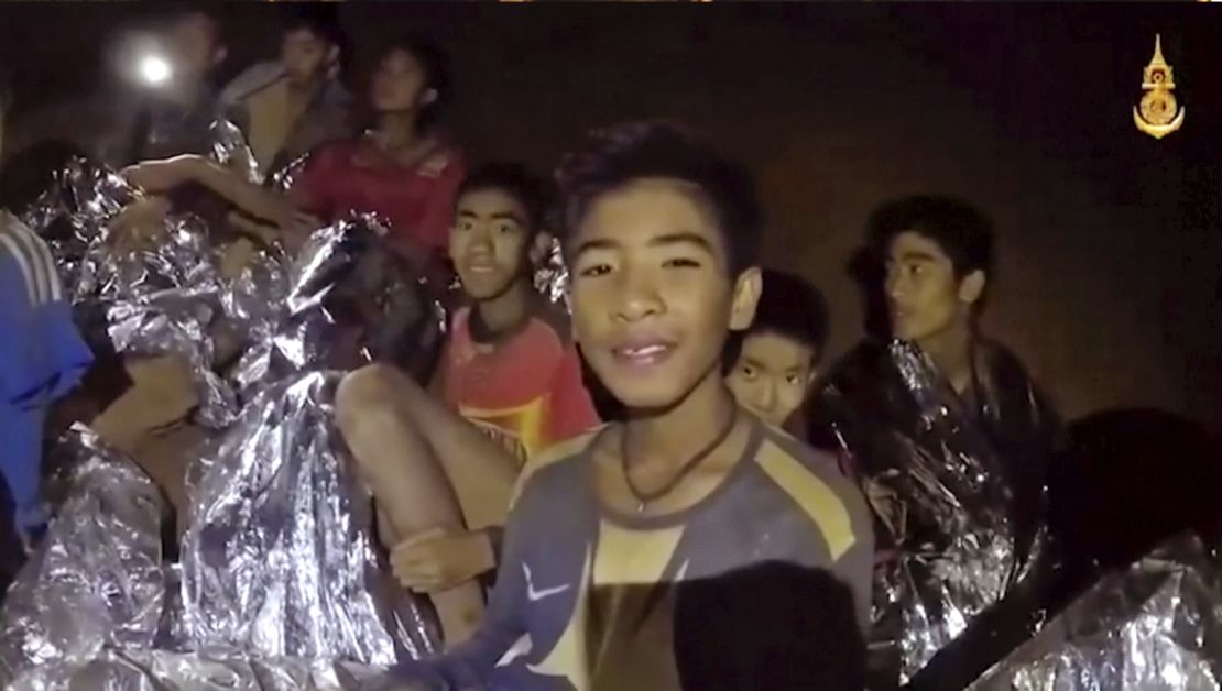 Some of the trapped boys smile as a Thai Navy SEAL medic offers assistance inside the cave on Tuesday. 