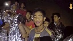 FILE - In this July 3, 2018, file image taken from video provided by the Royal Thai Navy Facebook Page, the boys smile as Thai Navy SEAL medic help injured children inside a cave in Mae Sai, northern Thailand. The group was discovered July 2 after 10 days totally cut off from the outside world, and while they are for the most physically healthy, experts say the ordeal has likely taken a mental toll that could worsen the longer the situation lasts. (Royal Thai Navy Facebook Page via AP, File)
