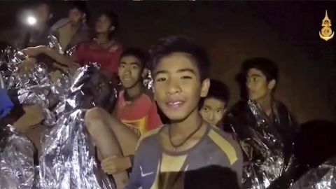 Some of the trapped boys smile as a Thai Navy SEAL medic offers assistance inside the cave on Tuesday.