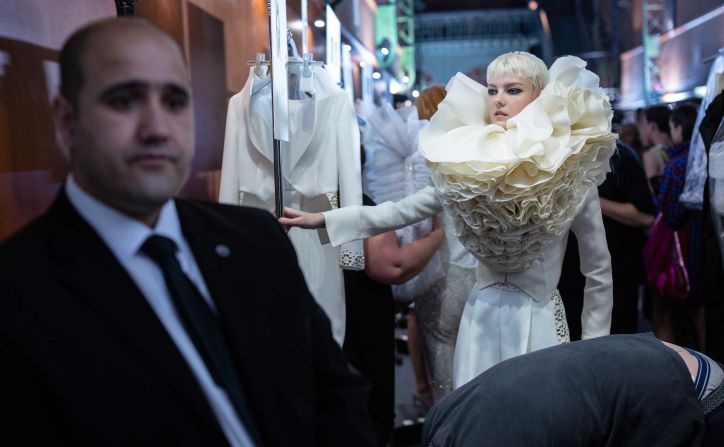 A security guard stands by as a model's dress is checked before the show. 
