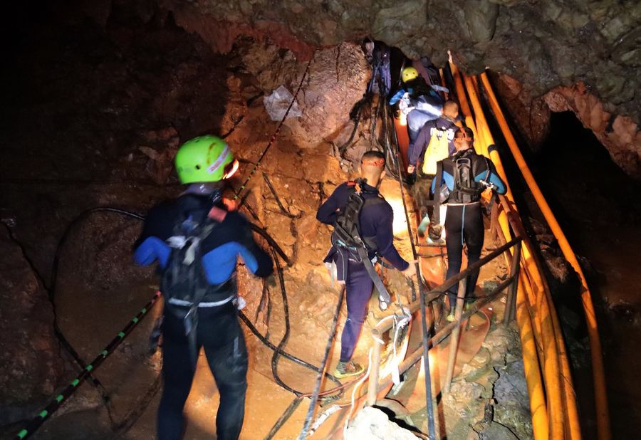 Thai military personnel walk into a cave during rescue operations.