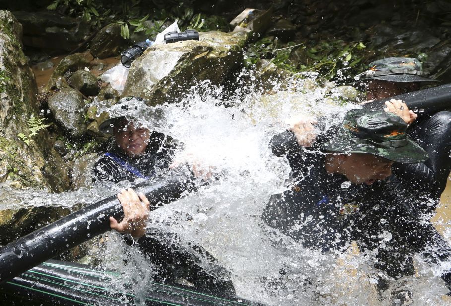 Thai soldiers work to connect pipes that help water from entering a cave.