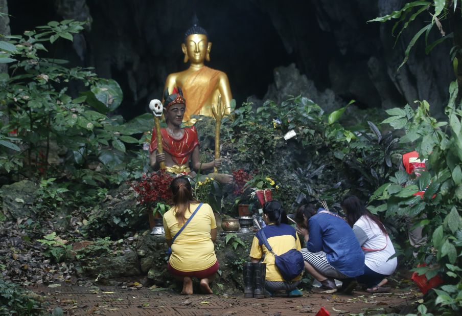 Family members pray in front of a Buddhist statue near the cave on July 8.