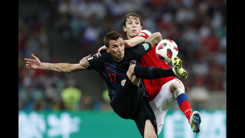 Croatia's Mario Mandzukic, left, challenges for the ball with Russia's Mario Fernandes during the quarterfinal match at <a href="index.php?page=&url=https%3A%2F%2Fwww.cnn.com%2F2018%2F06%2F14%2Ffootball%2Fgallery%2Fworld-cup-2018%2Findex.html" target="_blank">the World Cup</a> in Sochi, Russia, on Saturday, July 7. Croatia advanced to the semifinals after a dramatic penalty shootout when the game ended 2-2 on Saturday.