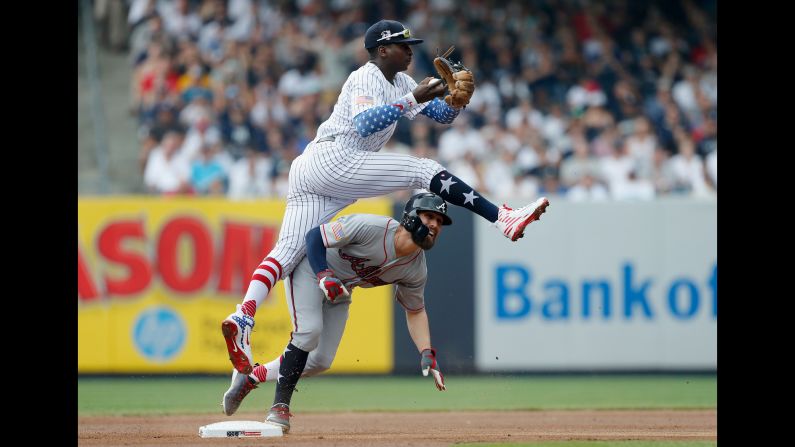 Didi Gregorius of the New York Yankees leaps over Ender Inciarte of the Atlanta Braves after a force out at second base during the first inning at Yankee Stadium on Wednesday, July 4, in New York.  