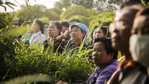 Onlookers cheer as a helicopter flies toward an airstrip near the cave to transport the fifth boy rescued to hospital.