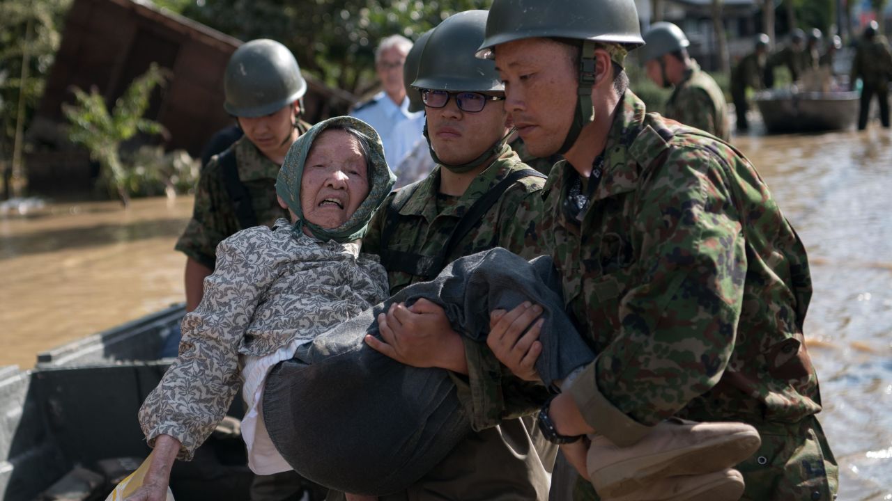 Soldiers carry an elderly woman away from flood water on July 8, 2018 in Kurashiki near Okayama, Japan.