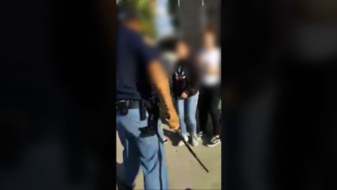 The officer extended his baton toward the crowd of children.