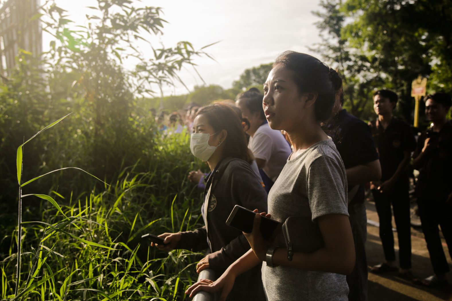 People watch and cheer as a helicopter flies toward an airstrip to transport one of the rescued boys to a hospital. Four boys were rescued on July 8, another four were rescued on July 9, and the rest were rescued on July 10.