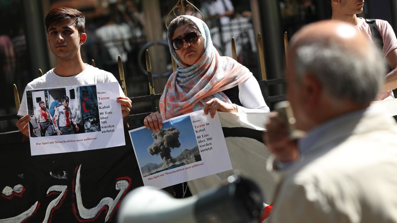 Afghans protesting against deportations in Berlin in May 2017 hold up photos of a bombing in Kabul.