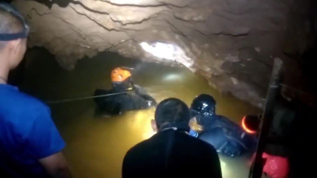Divers wave through floodwaters in the cave. Each rescue took multiple hours.