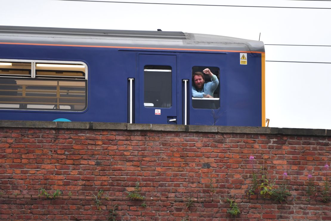A train driver in Manchester, England, stops and watches a big screen event showing England vs. Croatia.