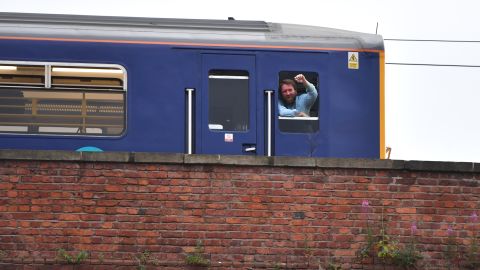 A train driver in Manchester, England, stops and watches a big screen event showing England vs. Croatia.