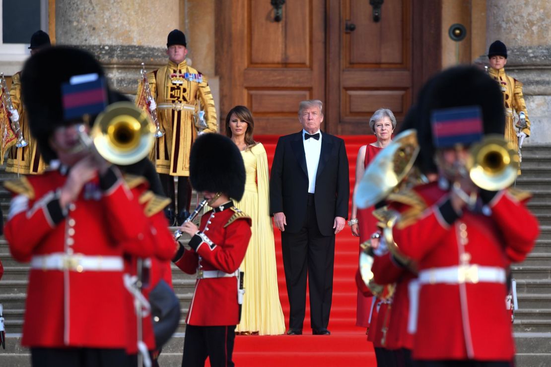 Britain's Prime Minister Theresa May, US President Donald Trump, and his wife US First Lady Melania Trump stand on steps in the Great Court watching the ceremonial welcome on July 12, 2018. 