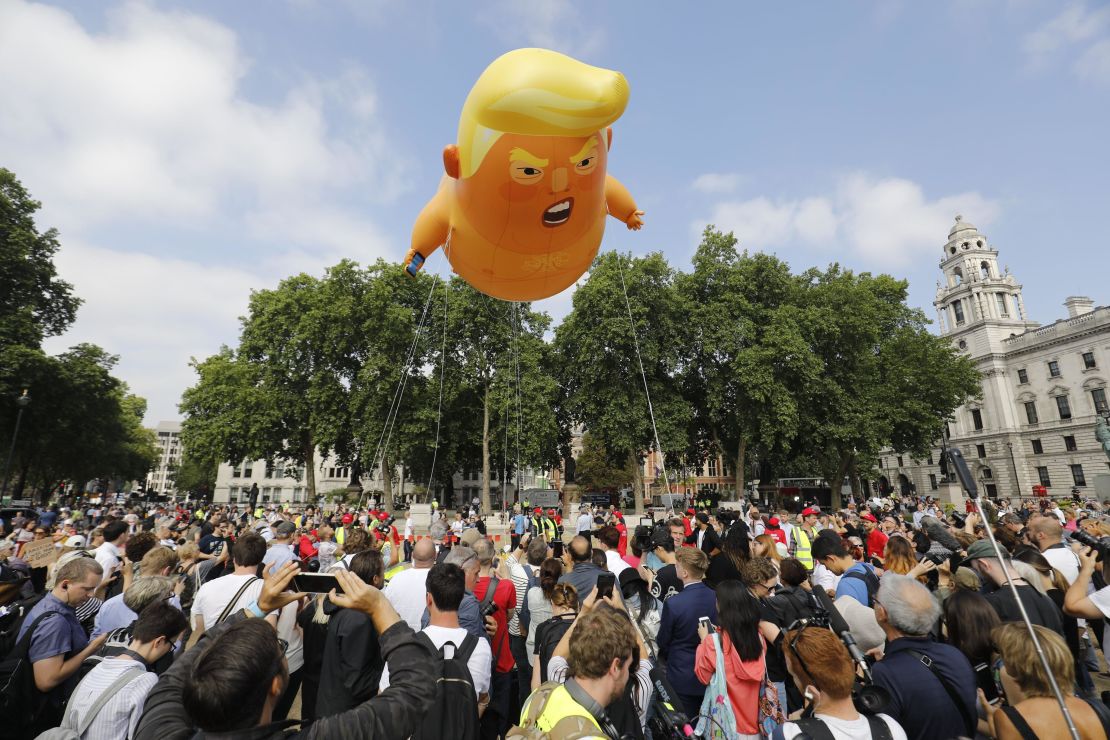 Activists inflate a giant balloon depicting US President Donald Trump as an orange baby Friday in Parliament Square in London.