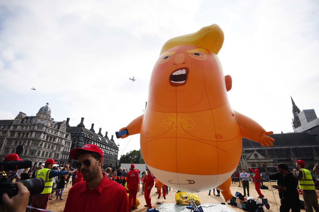 Activists wearing "Trump babysitter" hats hold onto the 'Trump Baby' balloon as it rises over Parliament Square.