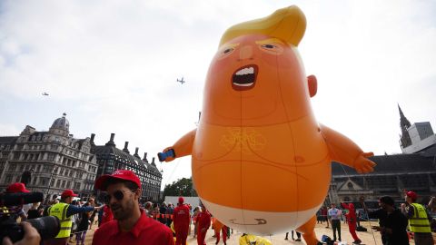 Activists wearing "Trump babysitter" hats hold onto the 'Trump Baby' balloon as it rises over Parliament Square.