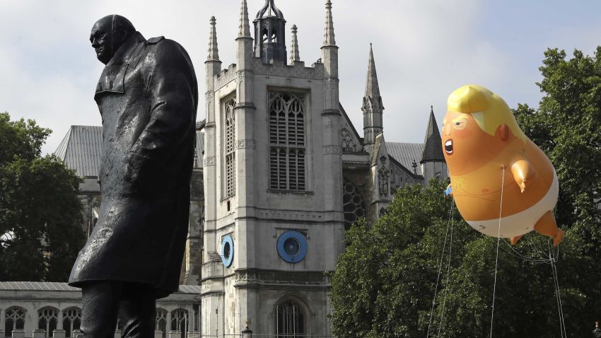 A six-meter high cartoon baby blimp of U.S. President Donald Trump hovers next to the statue of former British Prime Minister Winston Churchill, as it is flown as a protest against his visit, in Parliament Square in London, England, Friday, July 13, 2018. (AP Photo/Matt Dunham)