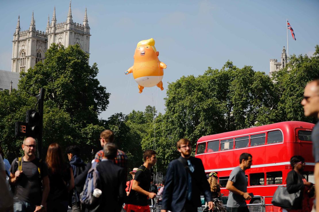 Pedestrians walk past as a giant "Trump Baby" balloon floats near the towers of Westminster Abbey.