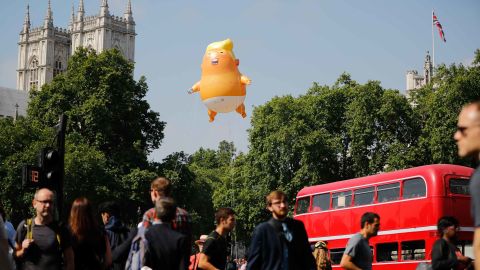 Pedestrians walk past as a giant "Trump Baby" balloon floats near the towers of Westminster Abbey.