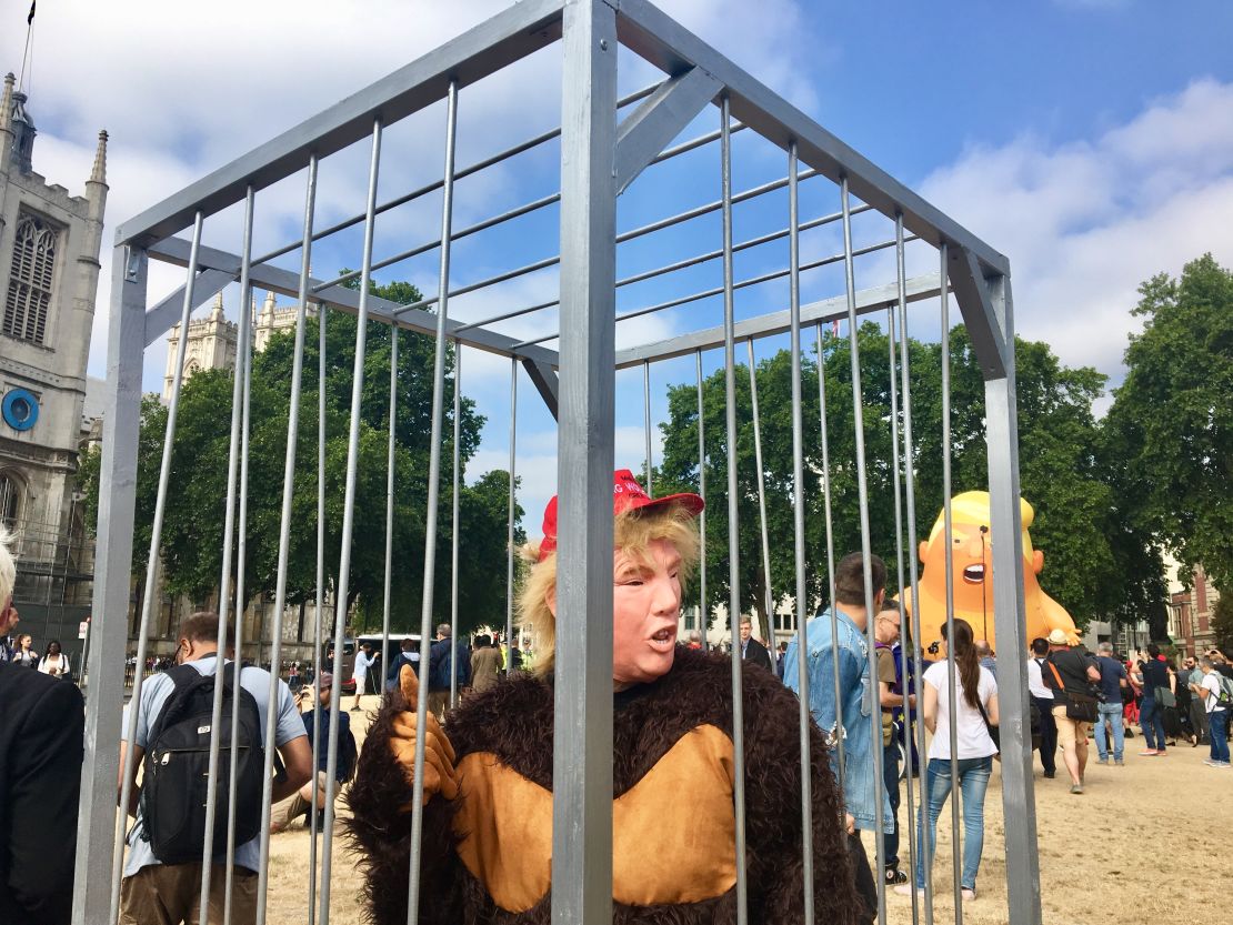 Gareth Steel, dressed in a Trump mask and gorilla costume, protests with an anti-Brexit group from inside a cage.