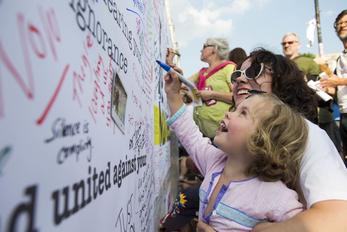 Anna Boyd watches as her daughter, Lyra, 3, adds her mark to the message wall.