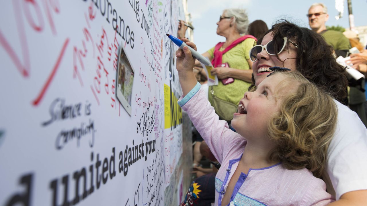 Anna Boyd watches as her daughter, Lyra, 3, adds her mark to the message wall.